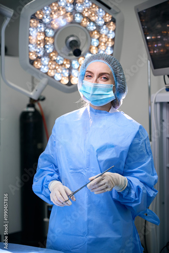 Caucasian woman in surgical scrubs using scissors in operating room