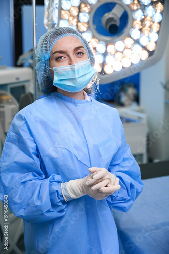 Female surgeon in operating room wearing surgical gown and mask