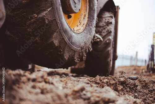 Canvas Print A close-up of an excavator tire lifted off the muddy ground due to a heavy load on the bucket shows the power and heaviness of construction machinery at work