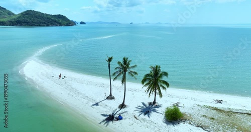 A mesmerizing aerial view of Laem Haad sandbar reveals dragon scale patterns beneath shallow waters. Tourists stroll along the white strip linking two island, forming a surreal tropical scene.