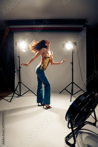 Fotografie Fashion model posing dynamically in studio photoshoot with strong backlighting,