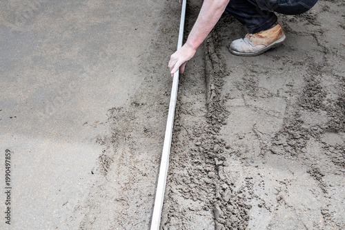 Quadro su tela Worker leveling concrete with screed for slab foundation