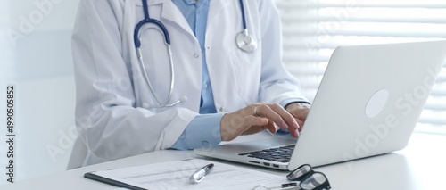 Φωτογραφία Female doctor documents patient information while working with digital devices at minimalist white workstation in medical office
