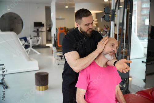 Two men in rehabilitation center performing neck massage therapy