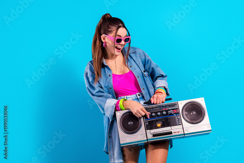 Φωτογραφία Young woman with boombox in retro 80s style outfit holding cassette player while