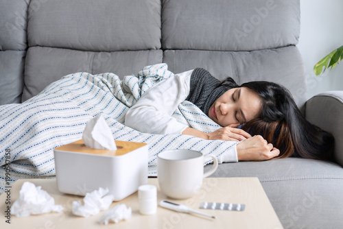 Young Asian woman get sick with changing seasons lie down on couch at home. Health problems, cold and flu