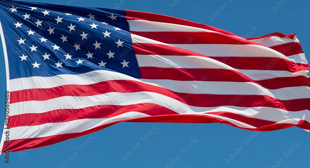 Fototapeta premium American flag waving in clear blue sky for Memorial Day, national symbol of freedom and sacrifice, US stars and stripes, patriotic veteran remembrance, Fourth of July celebration.