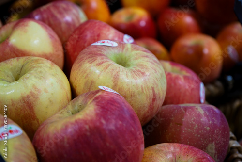 Closeup apples in the pile in the fruit shop with defocused red apple pile in background