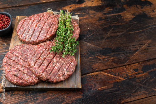 Fresh raw minced beef and lamb cutlets for burger. Overhead view on dark wooden background for barbecue.