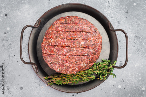 Raw mixed meat patty for burgers made from beef and lamb with herbs in pan. Light stone background with copy space for menu and design.