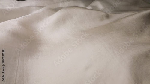 Soft natural silk fabric waving in the wind. Abstract background of smooth ivory and beige waves. Elegant flowing textile motion for luxury concepts. Lightweight organic material.