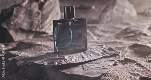 Aromatic blue perfume on dark volcanic rock.