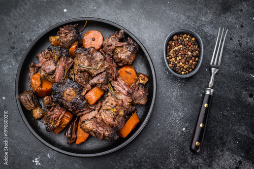 Homemade beef and lamb oxtail ragout in skillet, gelatin rich slow cooked meat with vegetables, overhead food photography