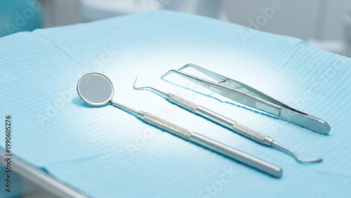 清潔に整えられた診療台の上に並ぶデンタルミラー、ピンセット、スケーラーのクローズアップ。衛生管理された歯科医院の診療準備や予防歯科、検診、クリーニング、医療サービスの信頼感を伝える、歯科・口腔ケア広告に適した高品質ビジュアル素材