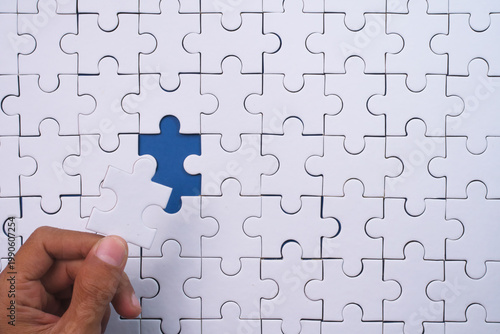 Hand placing final white puzzle piece into the empty blue gap