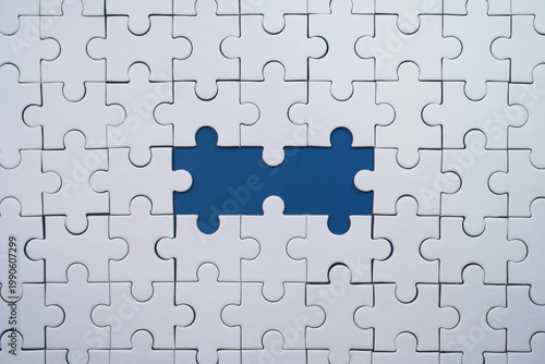 Incomplete white jigsaw puzzle with two significant missing blue pieces