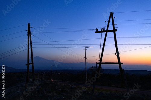 Obraz na plátně Power lines stretch across rural dusk landscape with distant hills