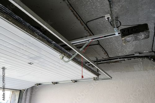 Foto sectional garage door with a mounted opener mechanism; metal tracks fixed to the