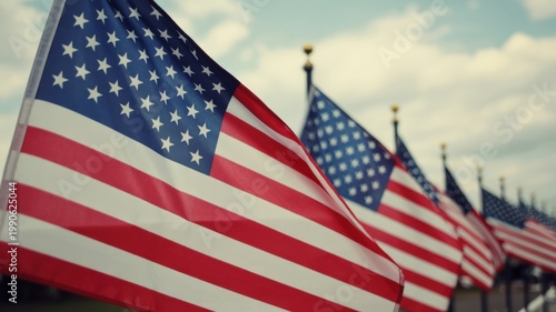 Close-up of American flags waving in the wind with blurred background and soft cloudy sky