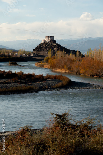 Serene river valley with stakna monastery and autumn foliage.
