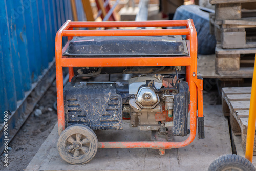 Obraz na płótnie Worksite power generator with orange steel cage, dusty engine housing, wheels, a