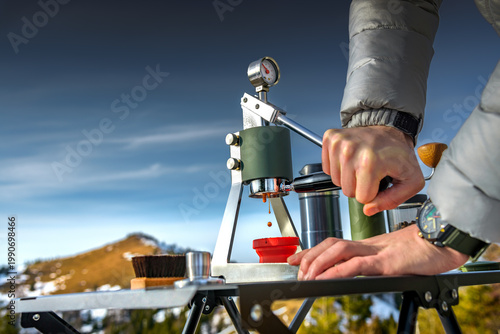 Man brewing espresso with manual lever coffee maker in mountains. Outdoor barista travel lifestyle