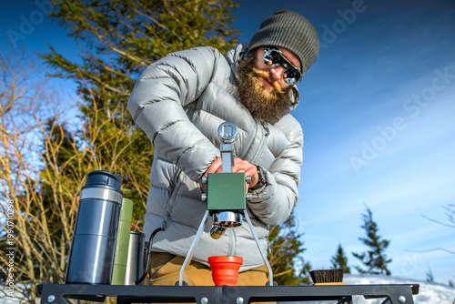 Manual lever espresso brewing outdoors, portable coffee machine in mountains, barista pressing lever, winter setup