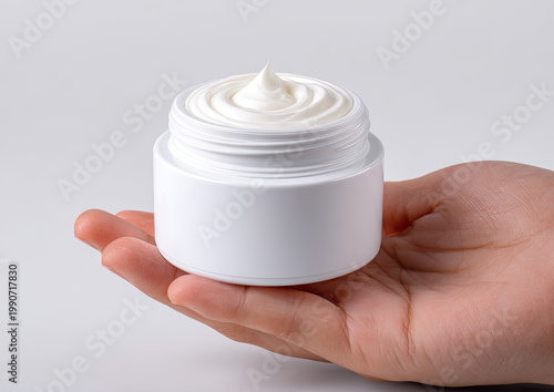 White cream in jar held in hand