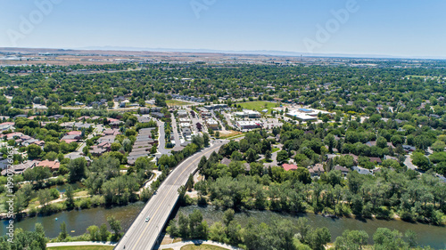 Aerial View of Highway Bridge Crossing River Through Lush Green Suburban Neighborhoods in Summer