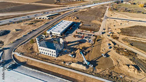 Aerial View of Multi-Story Commercial Office Building Under Active Construction with Crane Adjacent to Highway