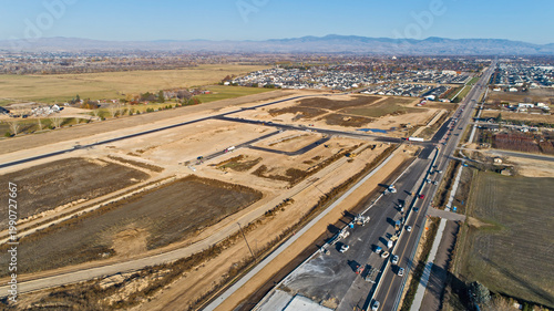 Aerial View of Large New Residential Development Under Construction Along Busy Highway with Mountain Range Backdrop