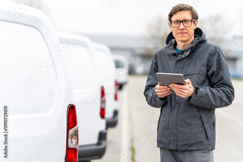 Canvas Print Fleet manager with digital tablet supervising rows of white delivery vans