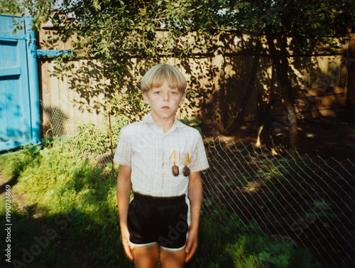 Authentic 1990s boy with medals portrait in backyard, childhood achievement concept
