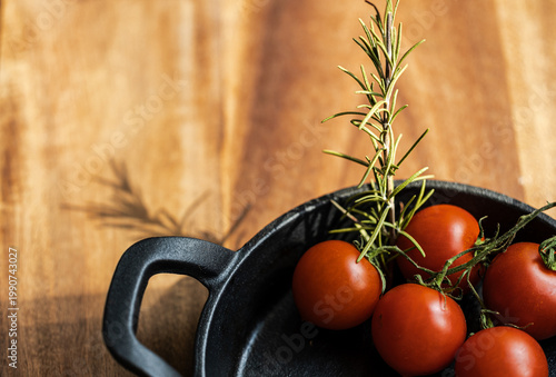 Fotografie Culinary still life of juicy red tomatoes in a black pan and garlic cloves on a
