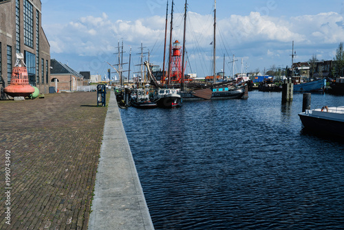 Fotografie Wide angle view of historic sailing ships and a red lighthouse boat moored at a