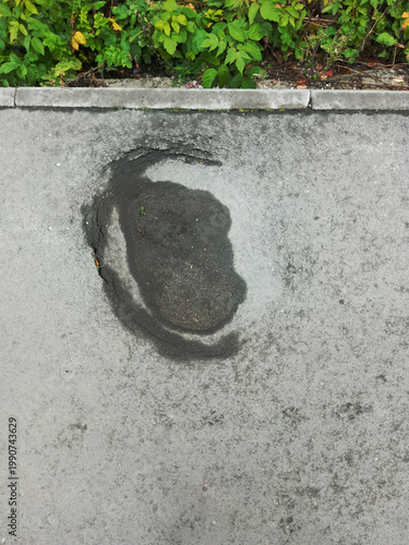 Pothole in the asphalt sidewalk. View from above.