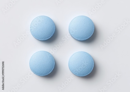 Four uniform light blue circular tablets arranged in a square formation on a white surface