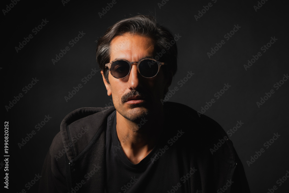Obraz premium Mysterious man in sunglasses captures intrigue in shadowy setting
