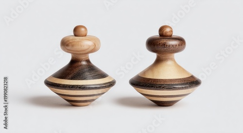 Two wood spinning tops, one lighter, one darker, on a white background