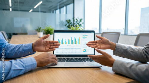 Business presentation showing colorful data charts on laptop screen in meeting room