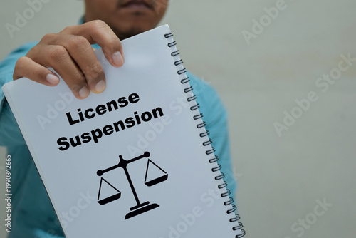 Businessman holds in hands a book with the name of the license suspension.