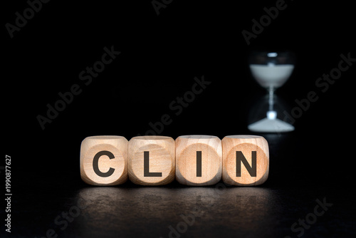 CLIN abbreviation on wooden blocks. Dark clinical trials and medical research concept with hourglass.