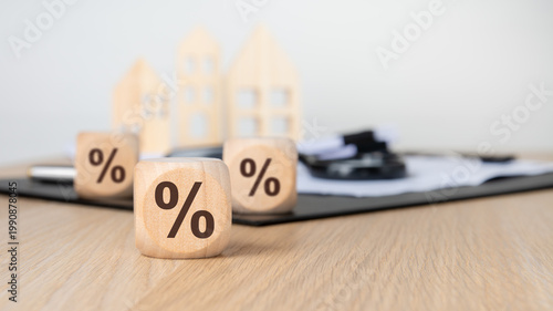 Multiple percentage signs on wooden blocks. Blurred houses and documents. Real estate mortgage concept.