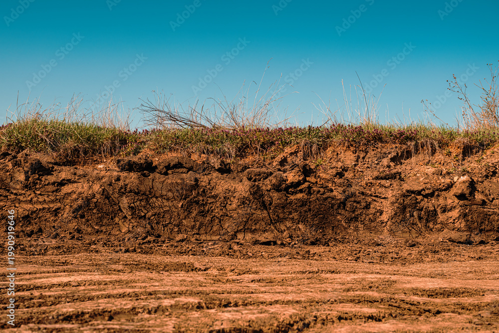 Fototapeta premium Excavated dirt road construction site under clear blue sky, earthworks and infrastructure development concept