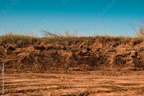 Excavated dirt road construction site under clear blue sky, earthworks and infrastructure development concept