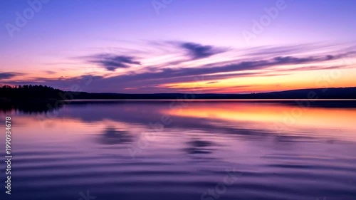 Sunset over calm reflective lake water.