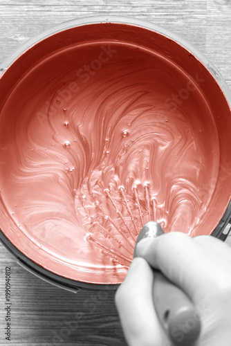 Person stirring mixing copper paint in a plastic paint tub container with a metal whisk. Decorating do it yourself home improvement concept.