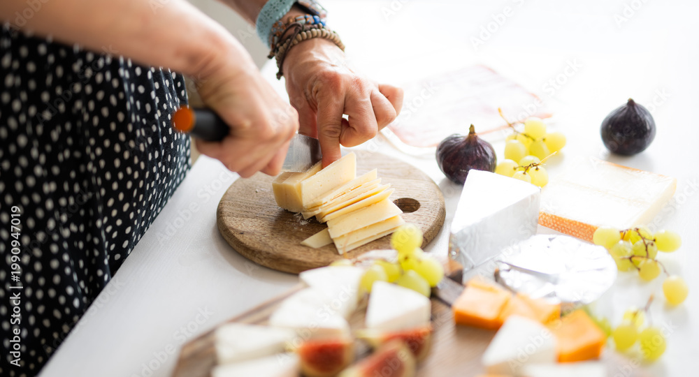Obraz premium Woman Cutting Parmesan Cheese On A Cutting Board With A Knife