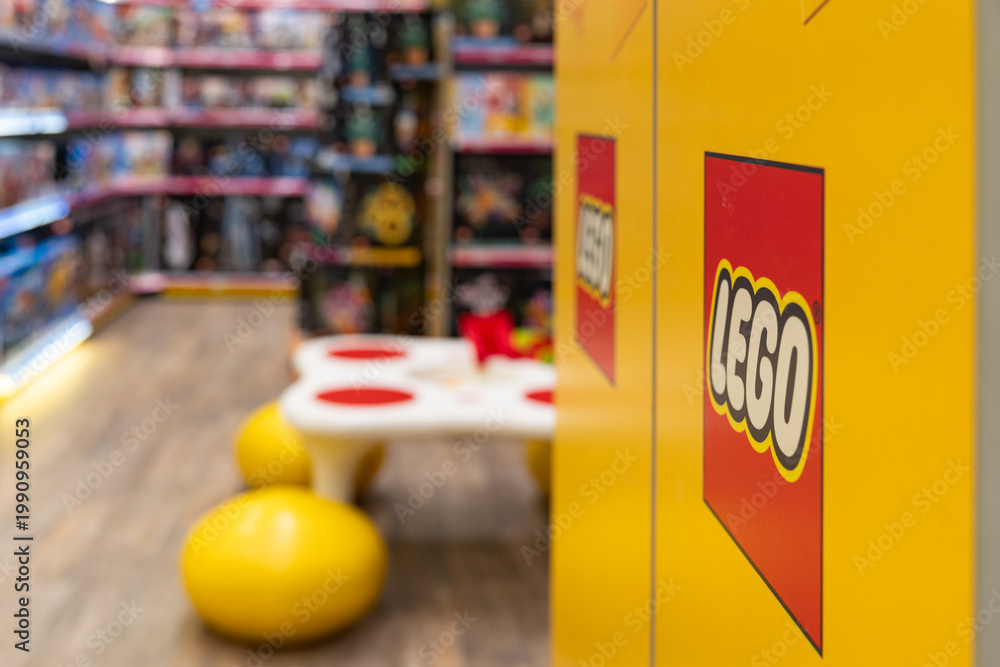 Fototapeta premium LEGO brand store interior with logo on yellow display close up