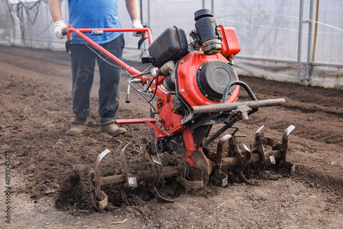 Φωτογραφία Gas powered rotary tiller cultivating soil in greenhouse for seedbed preparation